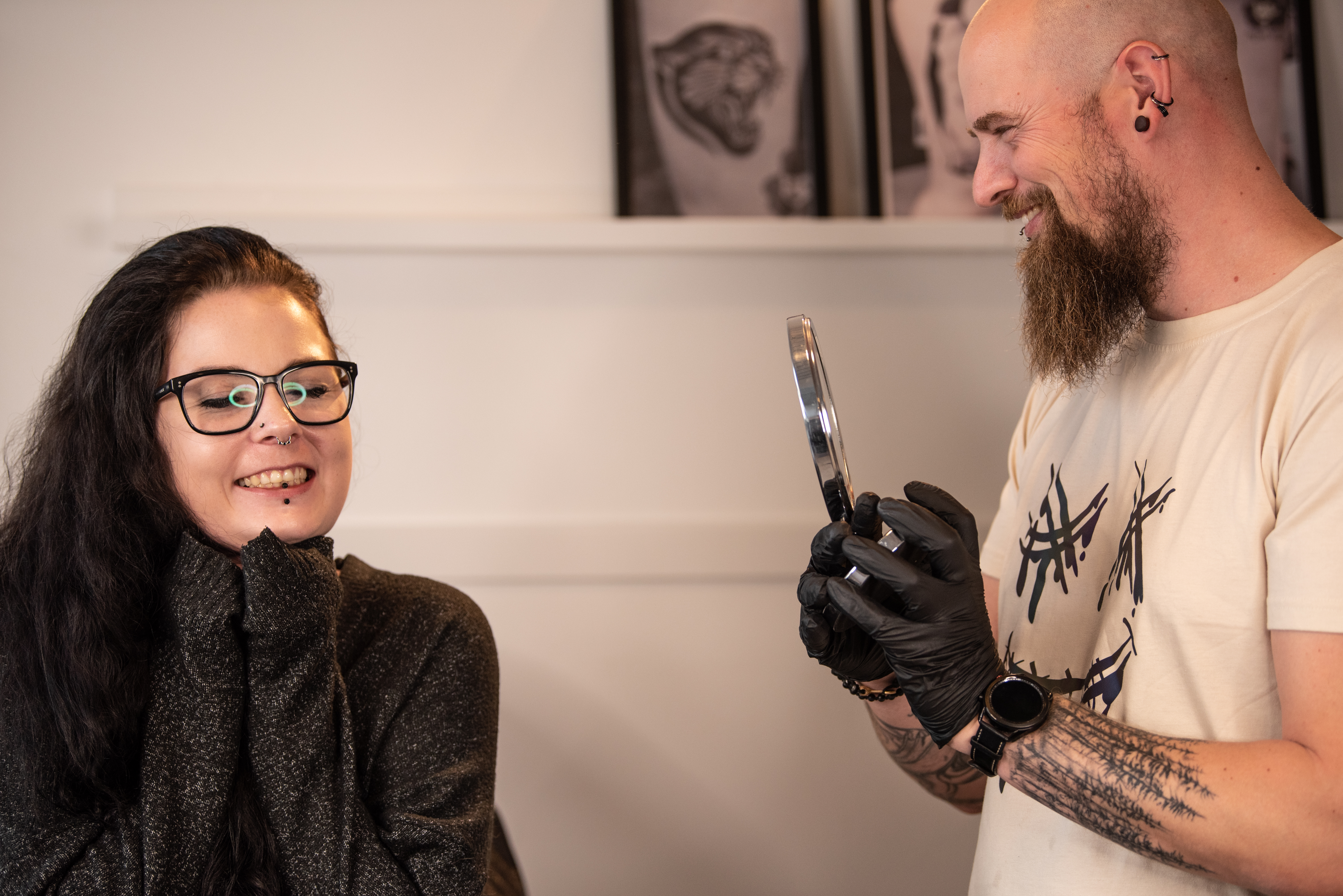 En glad kunde ser sin nye piercing i spejlet